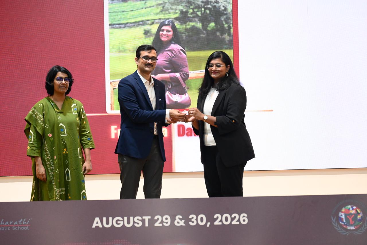 Frishthaa Dawulath being honoured on stage, with her photo and name on the screen behind and an event banner reading August 29 & 30, 2026.